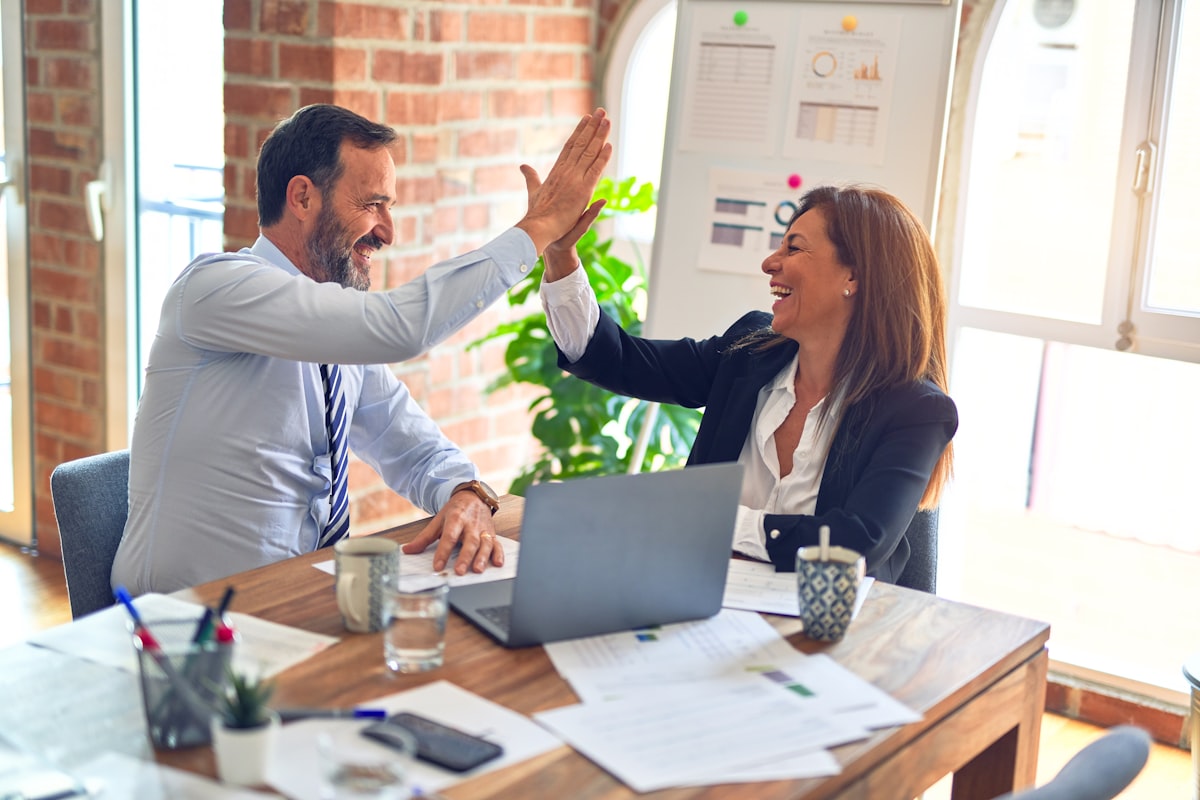 Two financial professionals celebrating a win in their office